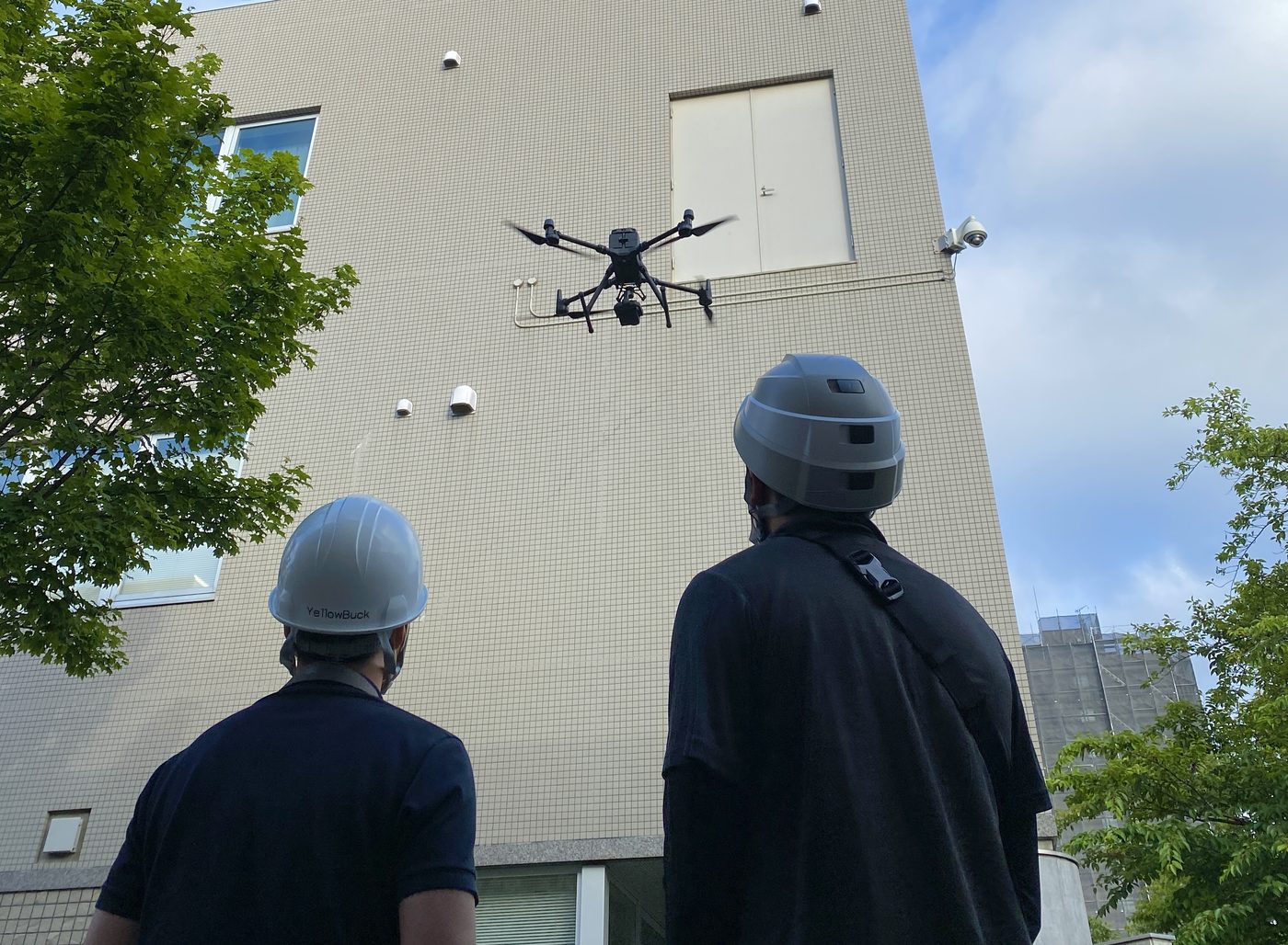 建物外壁の前でドローンを飛行させている調査風景